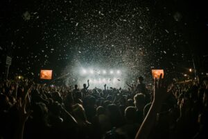 A massive crowd lit by the stage lights at a festival.
