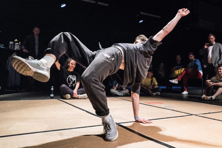 A young man breakdancing in an indoor studio.