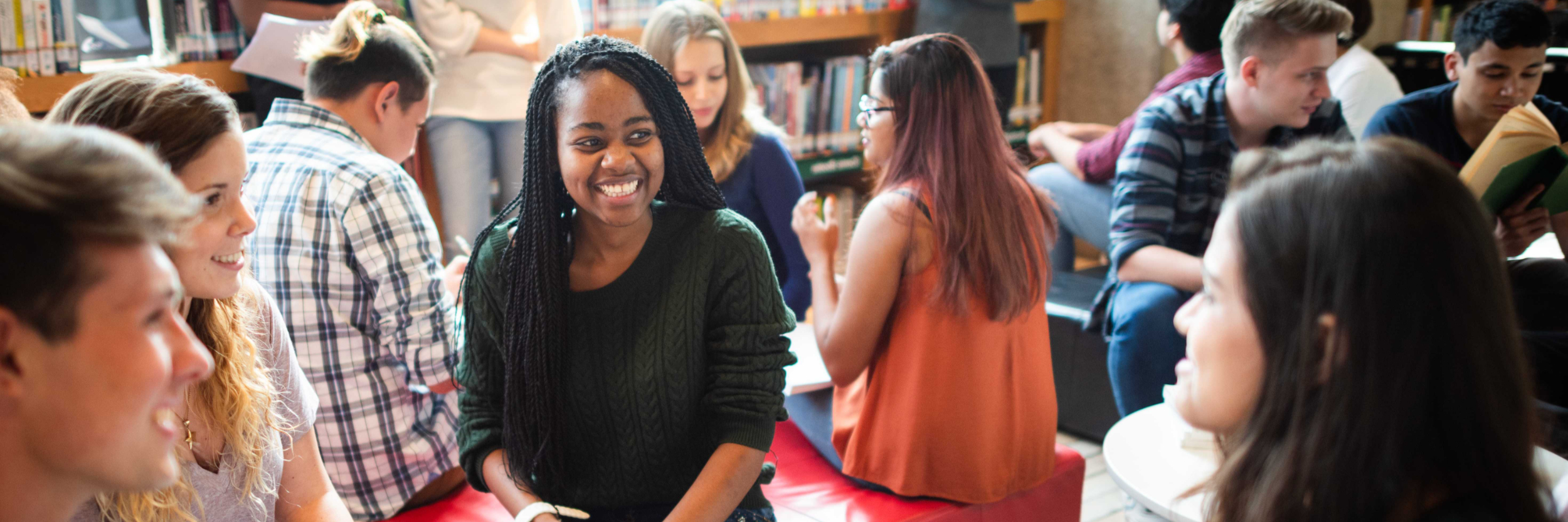 A diverse group of students seated in a library space.