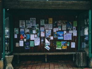 A bus shelter with lots of flyers posted against the back.