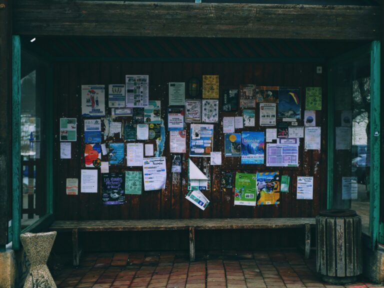 A bus shelter with lots of flyers posted against the back.
