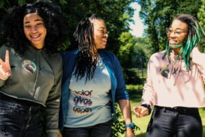 Three teenage girls laughing and smiling in a park.