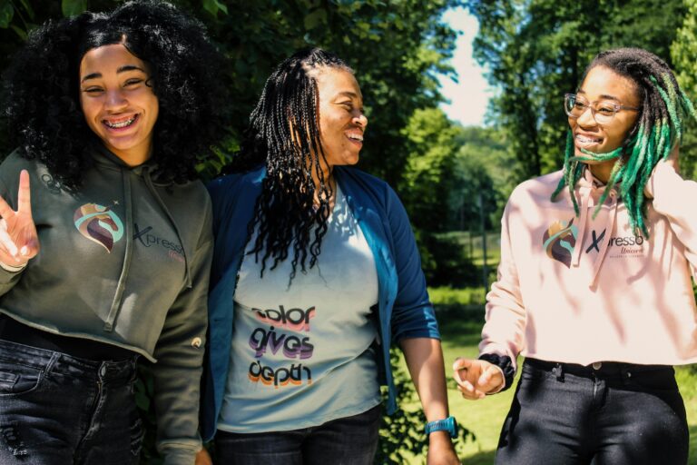 Three teenage girls laughing and smiling in a park.