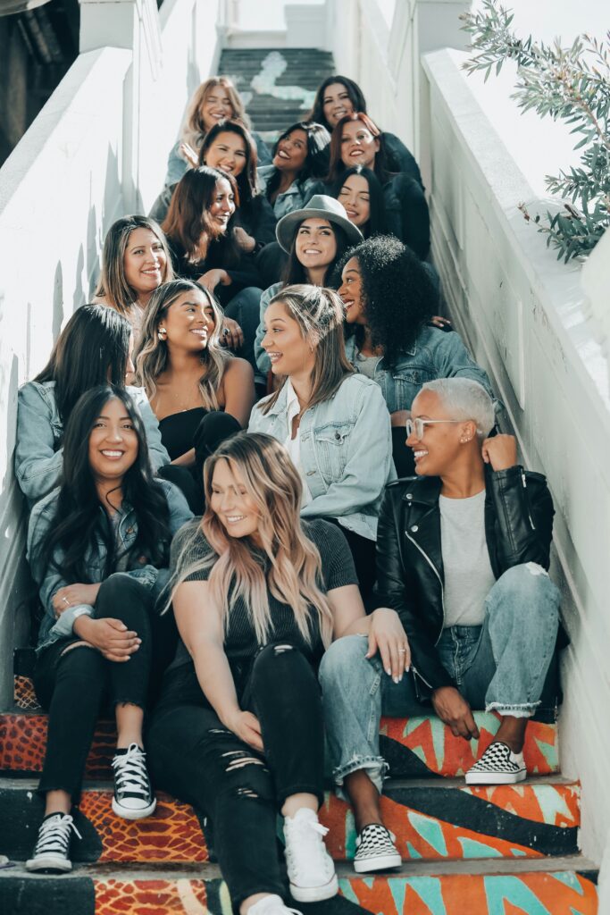 A large, diverse group of women, all dressed in coordinating blues, black and white, sat on graffiti-covered steps.