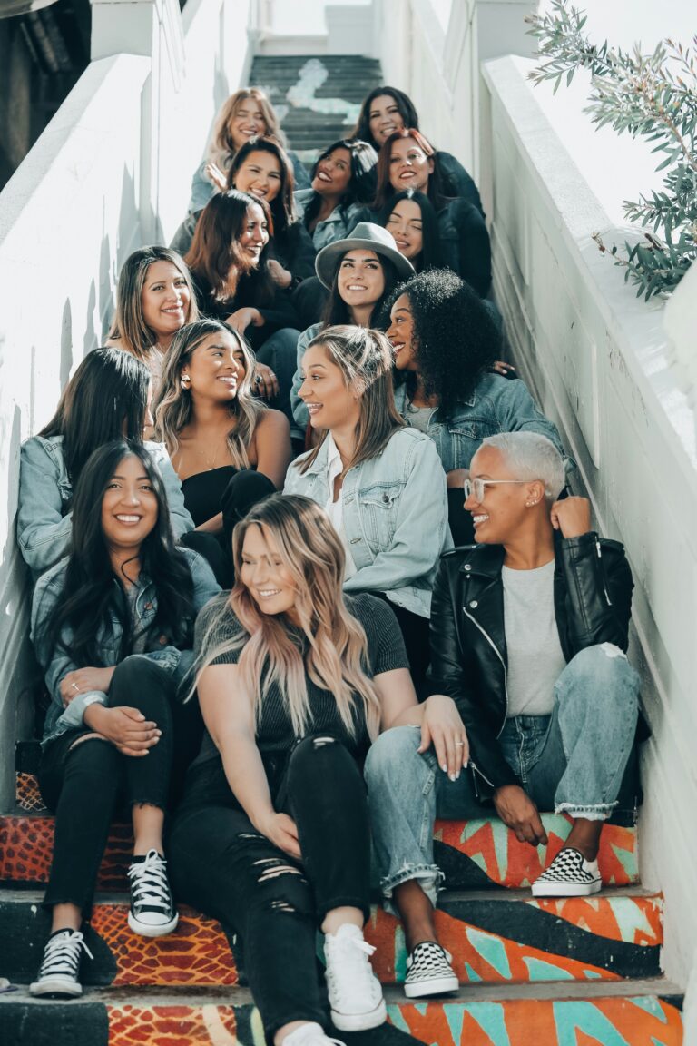 A large, diverse group of women, all dressed in coordinating blues, black and white, sat on graffiti-covered steps.